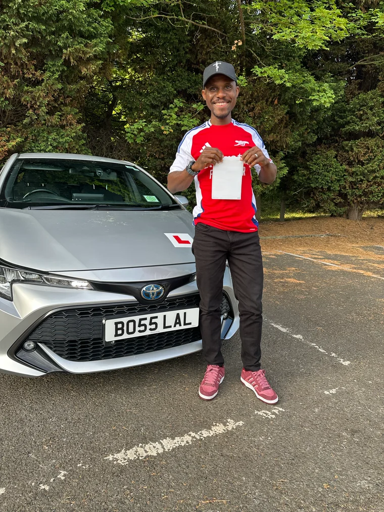Oppy in a red football shirt holding a faded pass certificate beside the training car.