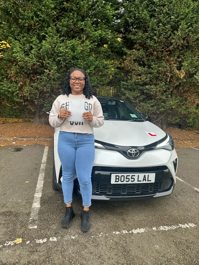 Allysa in a light sweatshirt holding a faded pass certificate in front of the training car.