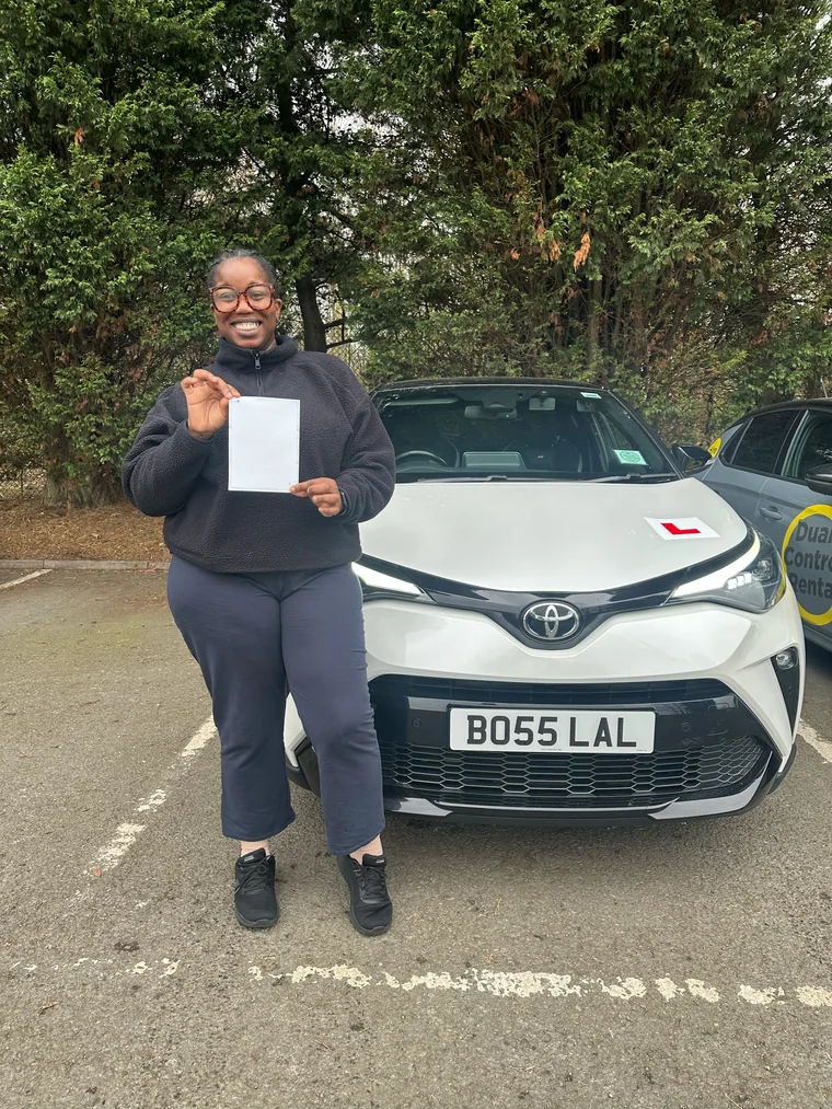 Chantel in a dark fleece holding a faded pass certificate beside the training car.