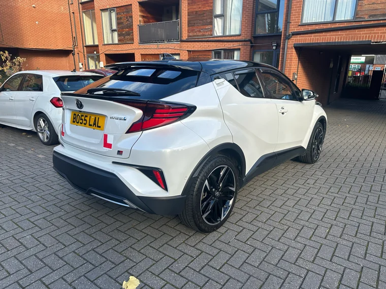 Rear-quarter view of the white Toyota C-HR GR Sport teaching car with its learner plate.